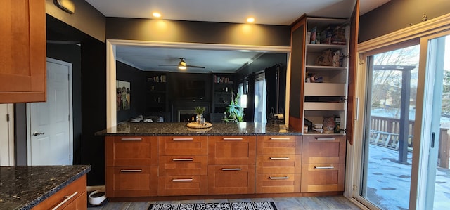 kitchen featuring ceiling fan, light wood-type flooring, and dark stone countertops