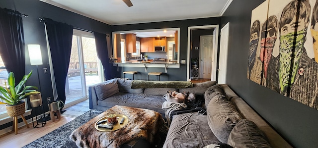 living room featuring light hardwood / wood-style flooring, ornamental molding, and ceiling fan