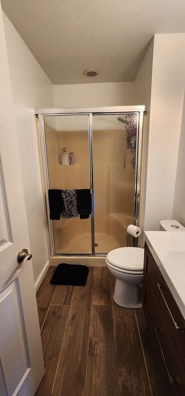 bathroom with hardwood / wood-style flooring, vanity, toilet, and an enclosed shower