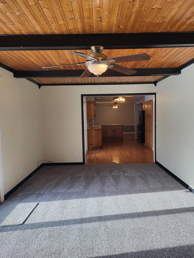 carpeted spare room with ceiling fan, beam ceiling, and sink