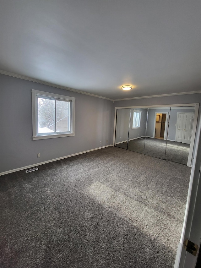 unfurnished bedroom with crown molding, a closet, and dark colored carpet