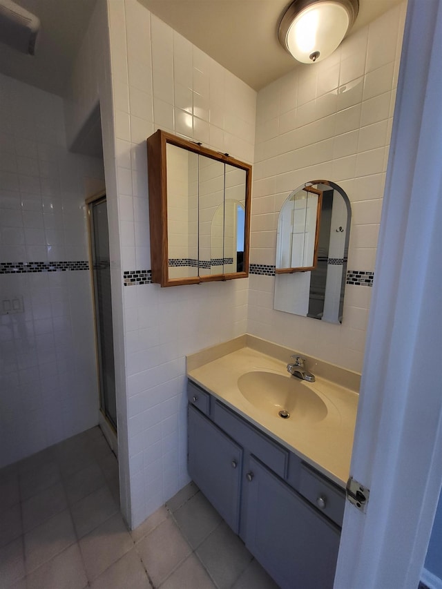 bathroom with tile patterned flooring, vanity, tile walls, and an enclosed shower