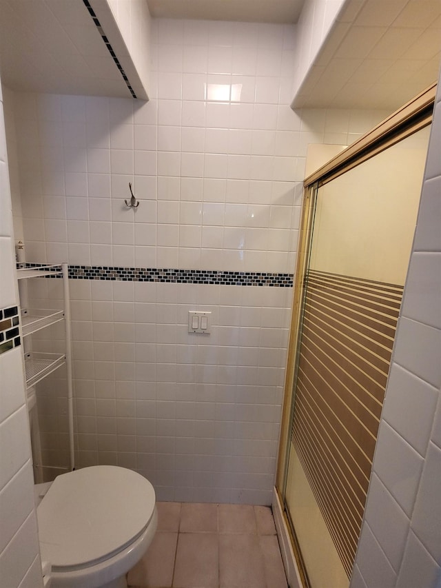 bathroom with tile patterned flooring, a shower with shower door, toilet, and tile walls