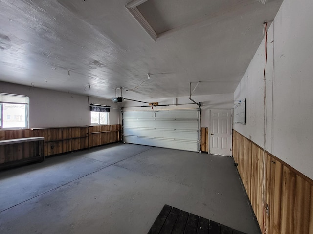 garage with a garage door opener and wood walls