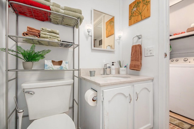 bathroom featuring vanity, washer / dryer, and toilet