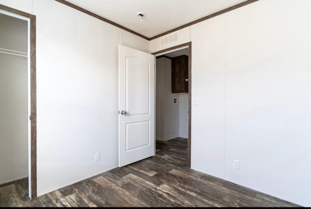 unfurnished bedroom with dark wood-type flooring and ornamental molding