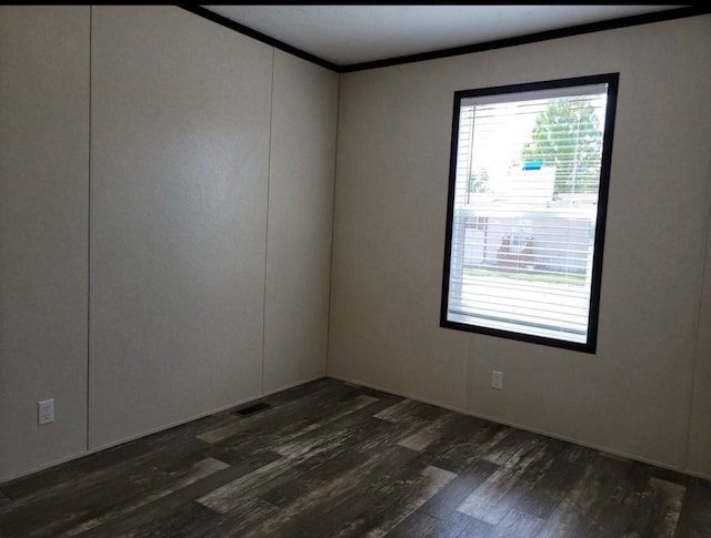 empty room featuring crown molding and dark wood-type flooring