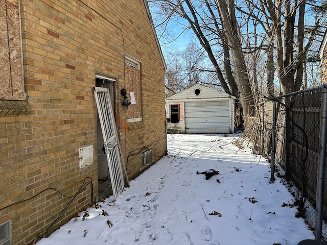 snow covered property featuring a garage and an outdoor structure