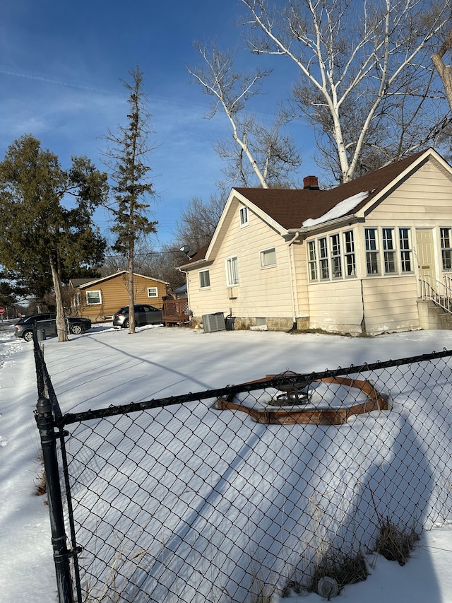 snow covered property with central AC