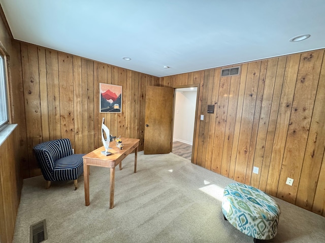 living area featuring wooden walls and carpet flooring