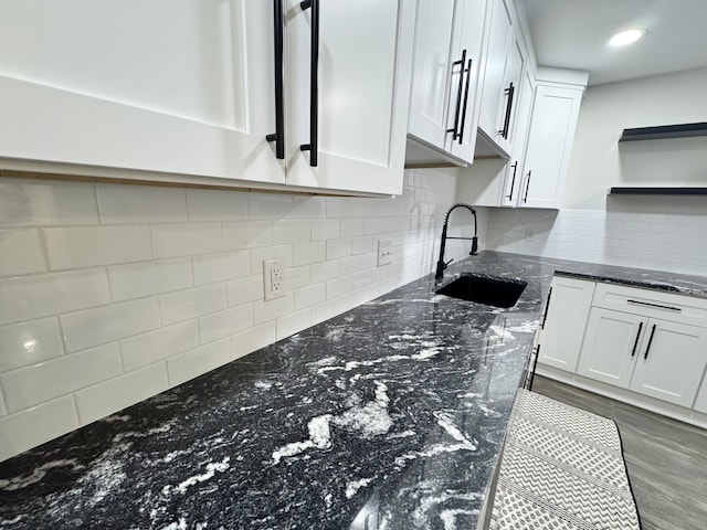 kitchen with dark wood-type flooring, sink, tasteful backsplash, dark stone countertops, and white cabinets