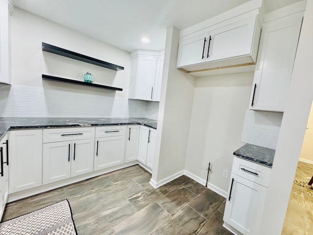 kitchen with white cabinetry, decorative backsplash, and dark stone countertops