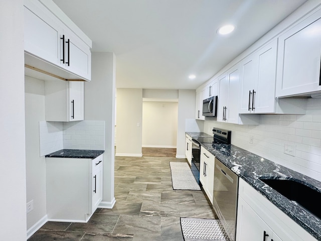 kitchen with sink, tasteful backsplash, dark stone countertops, appliances with stainless steel finishes, and white cabinets