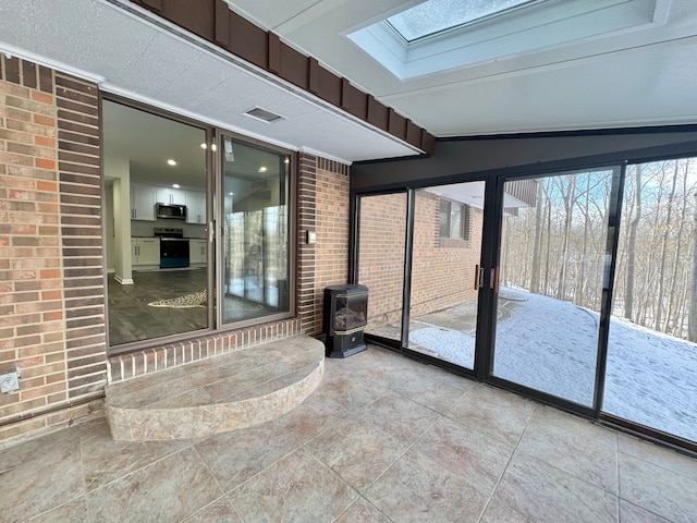 unfurnished sunroom with a skylight and a wood stove