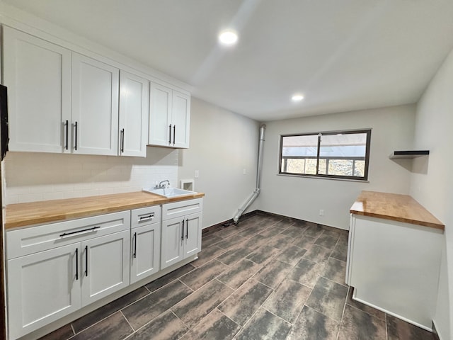 kitchen with sink, white cabinets, wood counters, and decorative backsplash