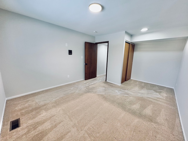 unfurnished bedroom with light colored carpet and a closet