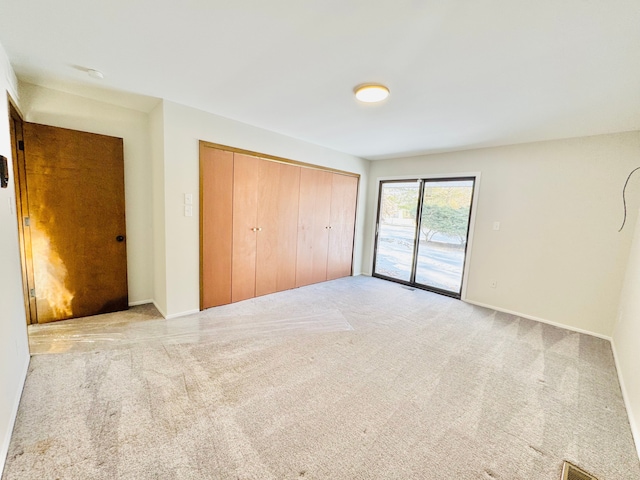 unfurnished bedroom featuring light carpet, access to outside, and a closet