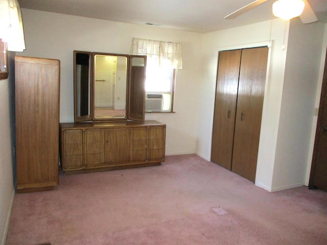 unfurnished bedroom featuring cooling unit, light colored carpet, ceiling fan, and a closet