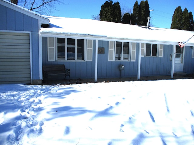 snow covered house featuring a garage