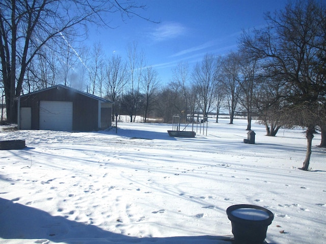 yard covered in snow featuring a garage and an outdoor structure