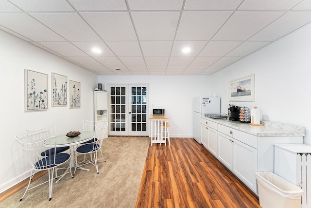 interior space with french doors, white cabinetry, white refrigerator, and dark wood-type flooring