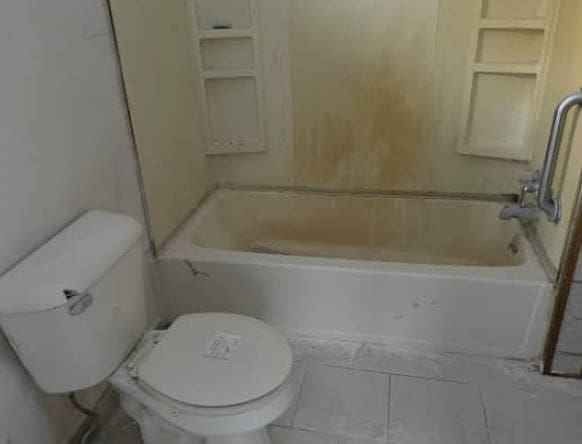 bathroom with tile patterned flooring, toilet, and  shower combination