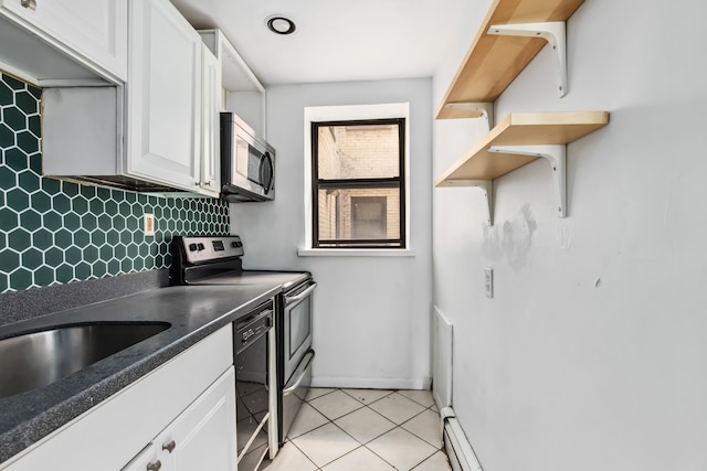 kitchen with light tile patterned floors, appliances with stainless steel finishes, a baseboard heating unit, tasteful backsplash, and white cabinets