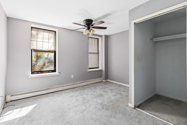 unfurnished bedroom featuring a baseboard heating unit, light carpet, ceiling fan, and a closet