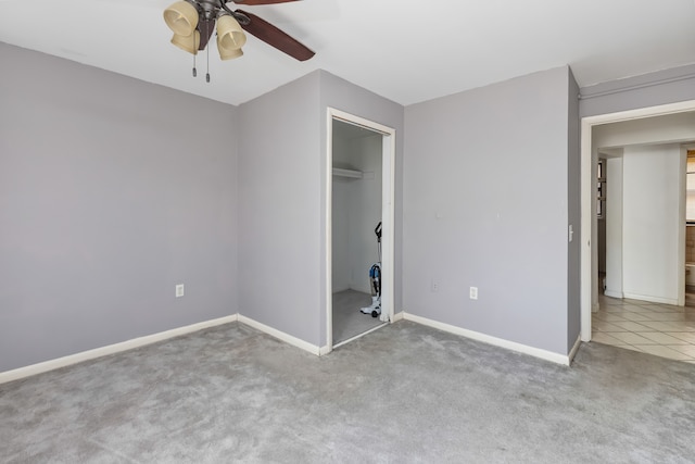 unfurnished bedroom with ceiling fan, light carpet, a closet, and a walk in closet