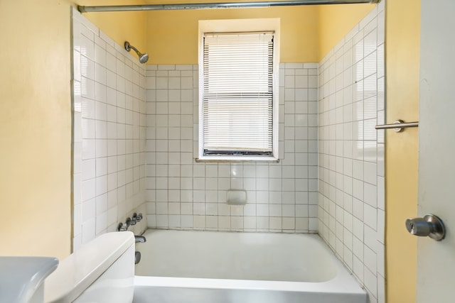 bathroom featuring plenty of natural light, toilet, and tiled shower / bath