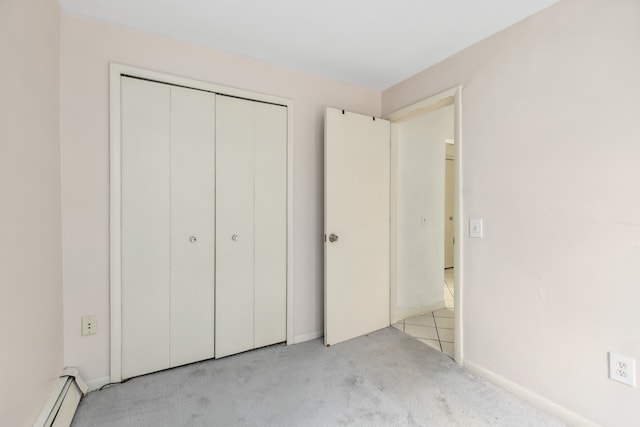 unfurnished bedroom with baseboard heating, light carpet, and a closet