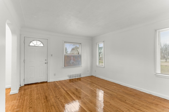 foyer with crown molding and light hardwood / wood-style flooring