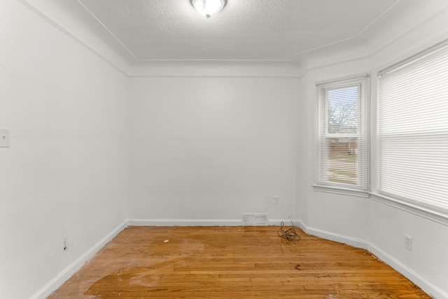 spare room featuring hardwood / wood-style floors and a textured ceiling