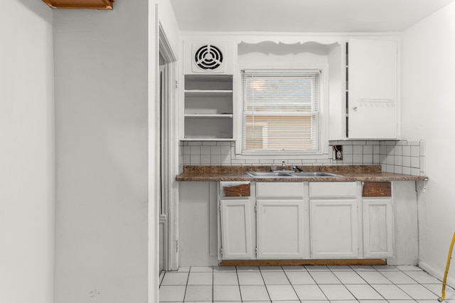 kitchen with sink, decorative backsplash, light tile patterned floors, and white cabinets