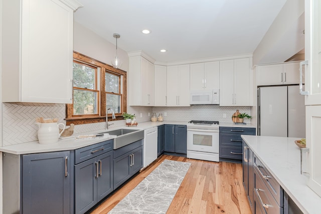 kitchen with sink, decorative light fixtures, light hardwood / wood-style flooring, white appliances, and white cabinets