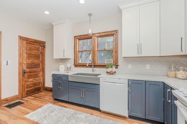 kitchen featuring sink, dishwasher, white cabinetry, decorative light fixtures, and light wood-type flooring