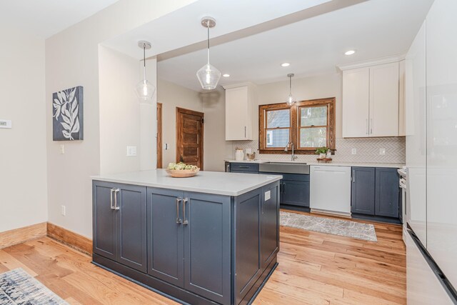 kitchen featuring blue cabinets, white cabinetry, dishwasher, sink, and hanging light fixtures