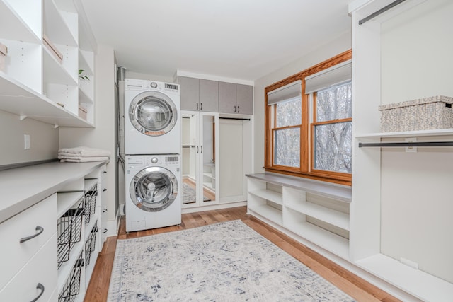 clothes washing area featuring light hardwood / wood-style flooring and stacked washing maching and dryer