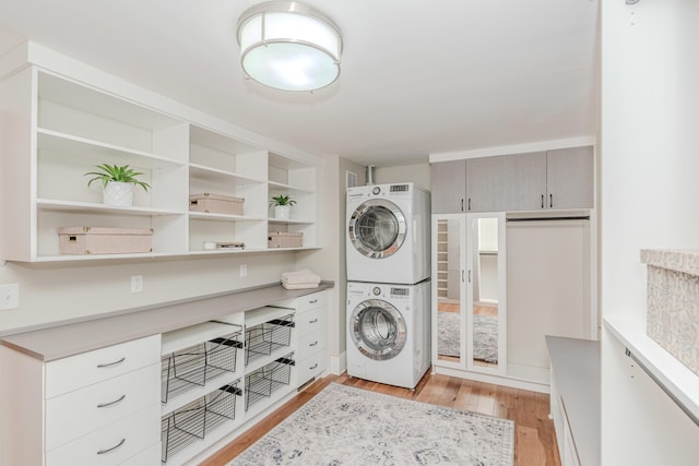 clothes washing area with stacked washer and dryer and light wood-type flooring