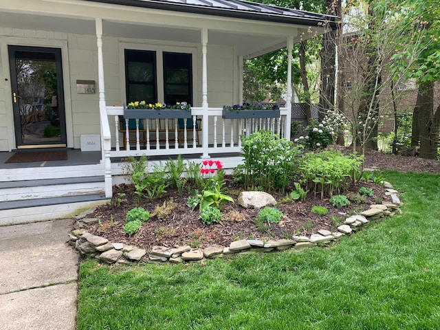 view of exterior entry featuring a lawn and covered porch