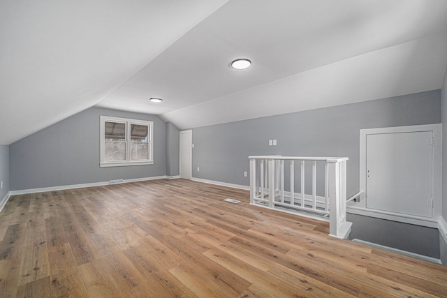 additional living space with lofted ceiling and light hardwood / wood-style flooring