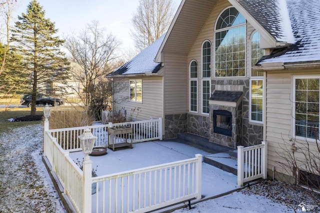 wooden terrace with exterior fireplace and a patio area