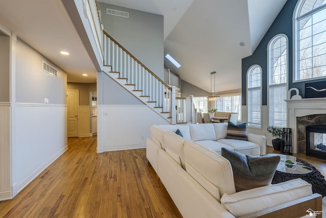 living room featuring a high end fireplace, vaulted ceiling, and wood-type flooring