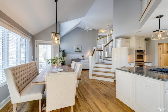 dining area featuring ceiling fan, high vaulted ceiling, and light hardwood / wood-style flooring