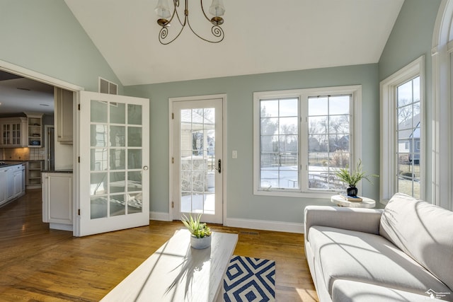 sunroom / solarium with lofted ceiling, a healthy amount of sunlight, and an inviting chandelier