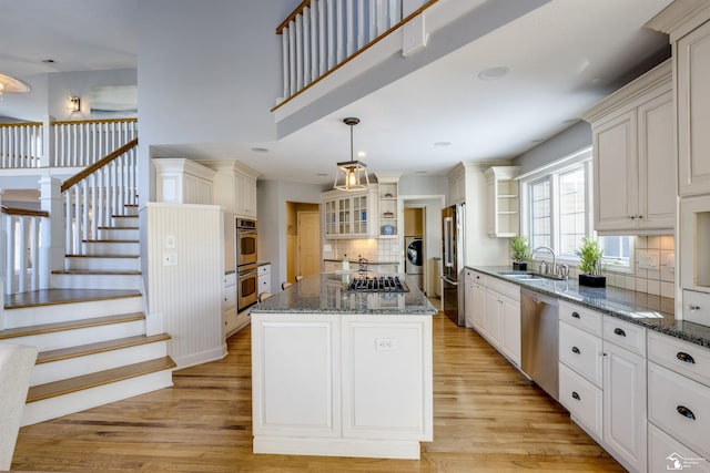 kitchen with a kitchen island, sink, backsplash, light hardwood / wood-style floors, and stainless steel appliances