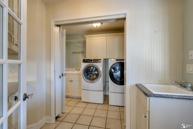 laundry room with cabinets, washing machine and clothes dryer, sink, and light tile patterned floors