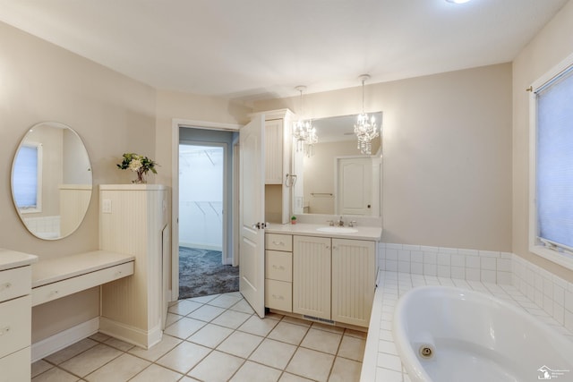 bathroom featuring tile patterned flooring, vanity, tiled bath, and an inviting chandelier