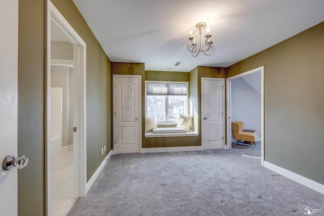 unfurnished bedroom with an inviting chandelier, light colored carpet, and a textured ceiling