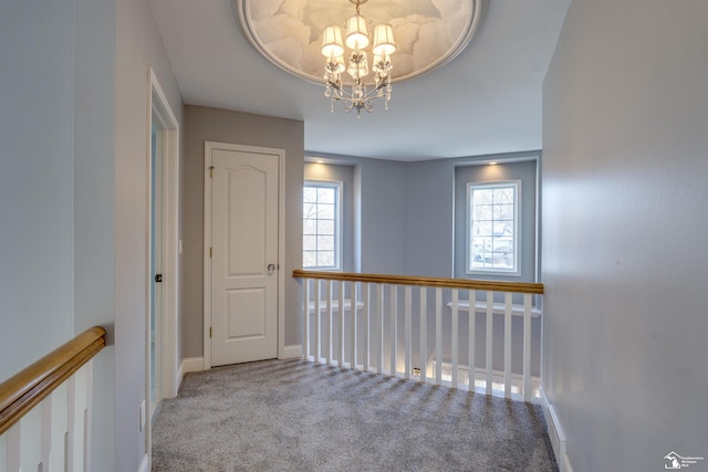 hall with a notable chandelier and light colored carpet